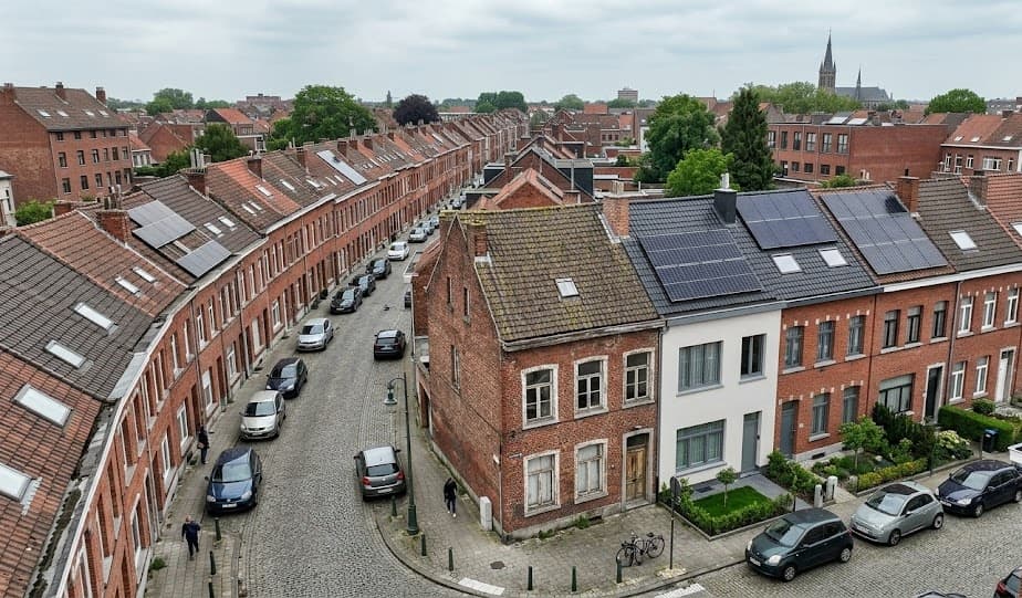 Luchtfoto van typische Antwerpse rijwoningen met contrast tussen gerenoveerde woning met zonnepanelen en ongerenoveerde buurhuizen